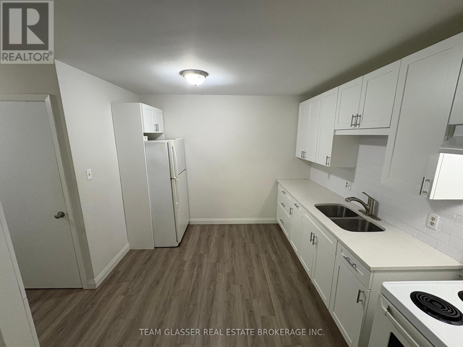 A kitchen with white cabinets and a wooden floor.