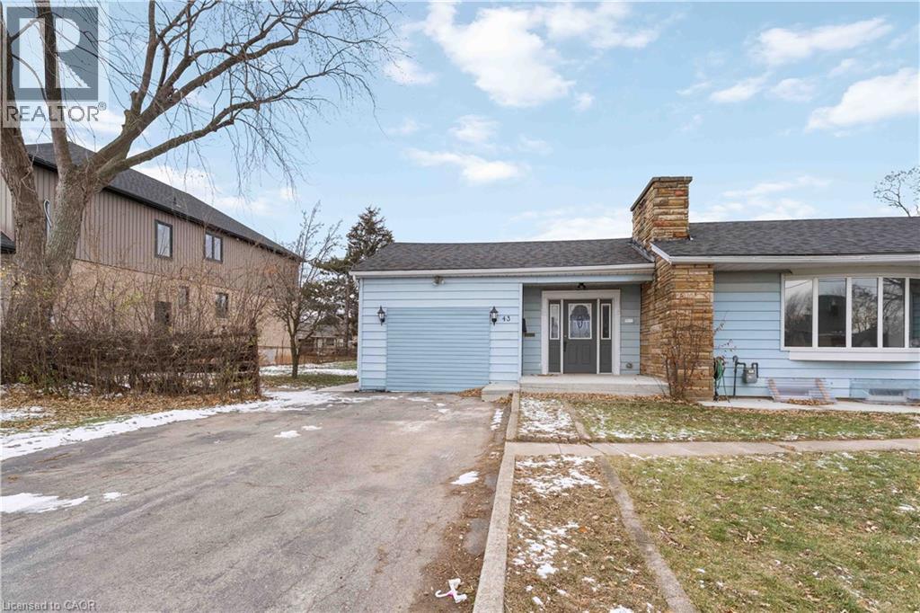 A blue house with a grey garage door is surrounded by a snowy landscape.