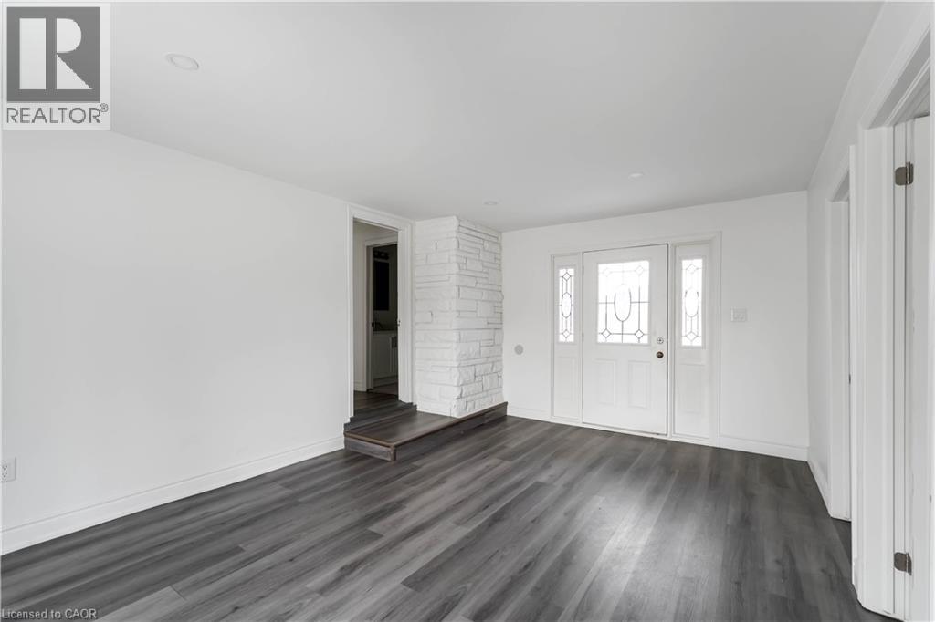 A spacious room with wooden flooring and white walls.