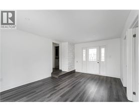 A spacious room with wooden flooring and white walls.