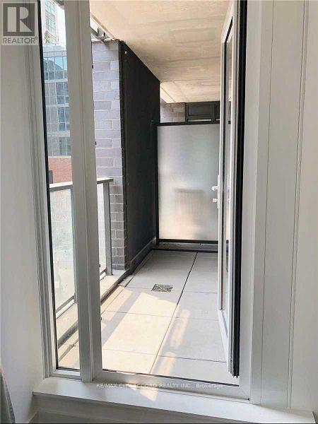A view from a window into a kitchen with a refrigerator.