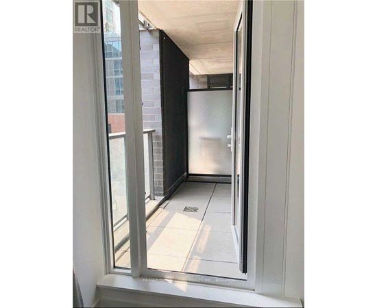 A view from a window into a kitchen with a refrigerator.