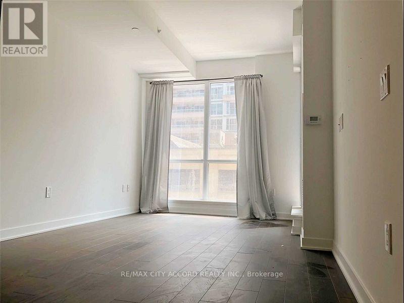 A spacious room with a large window and curtains.