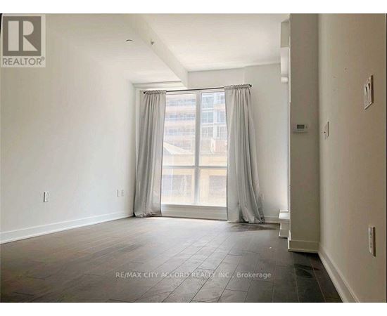 A spacious room with a large window and curtains.