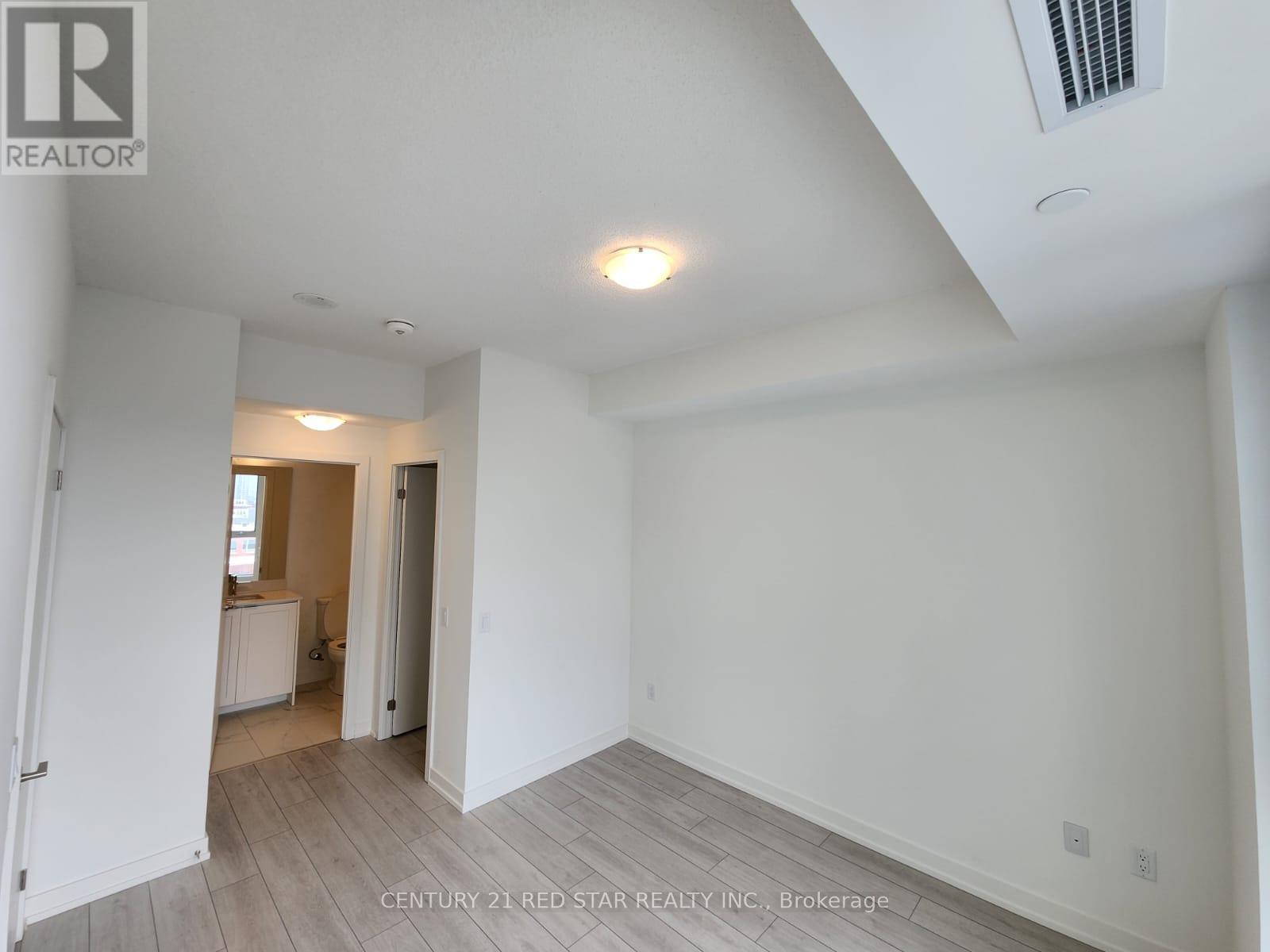 A spacious room with white walls and a wooden floor.