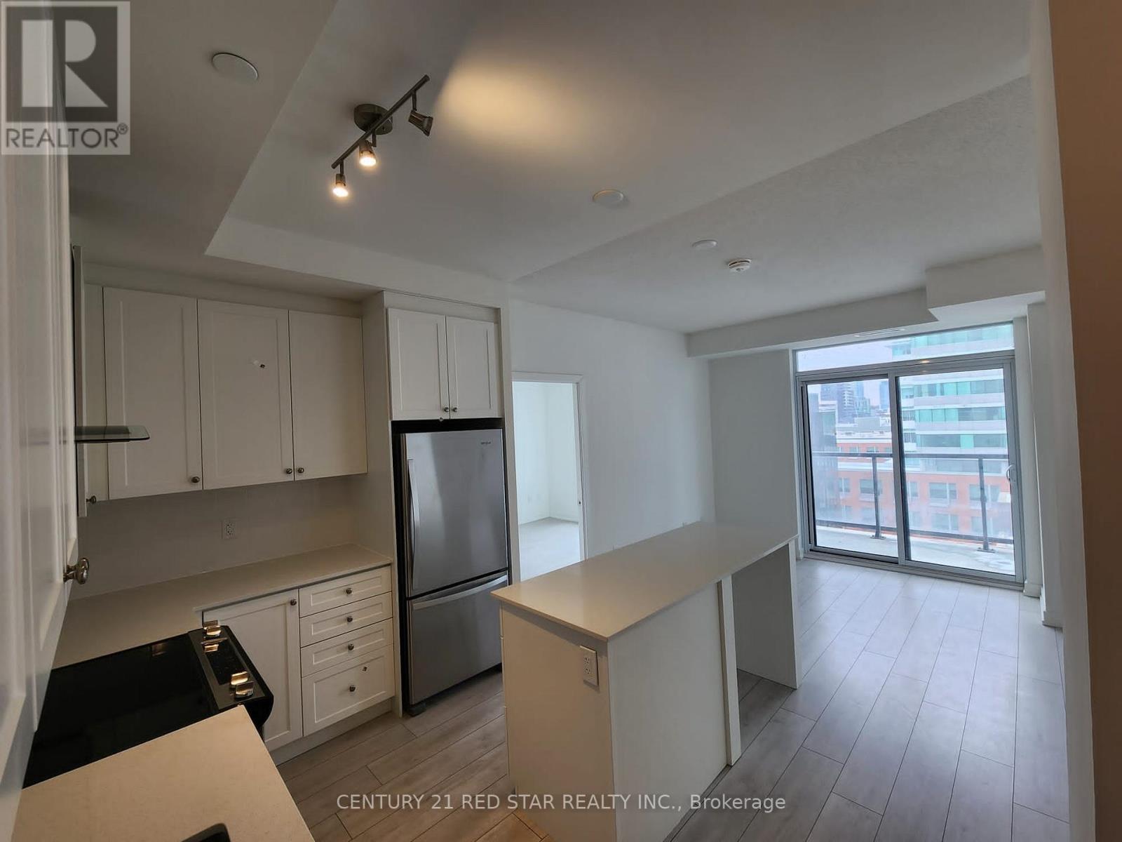 A kitchen with white cabinets and a refrigerator.