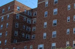 a tall brick building on the side of a sidewalk