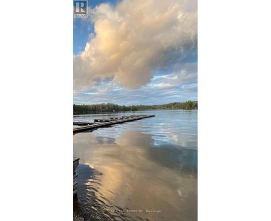 A body of water with a dock and a cloudy sky reflected in the water.