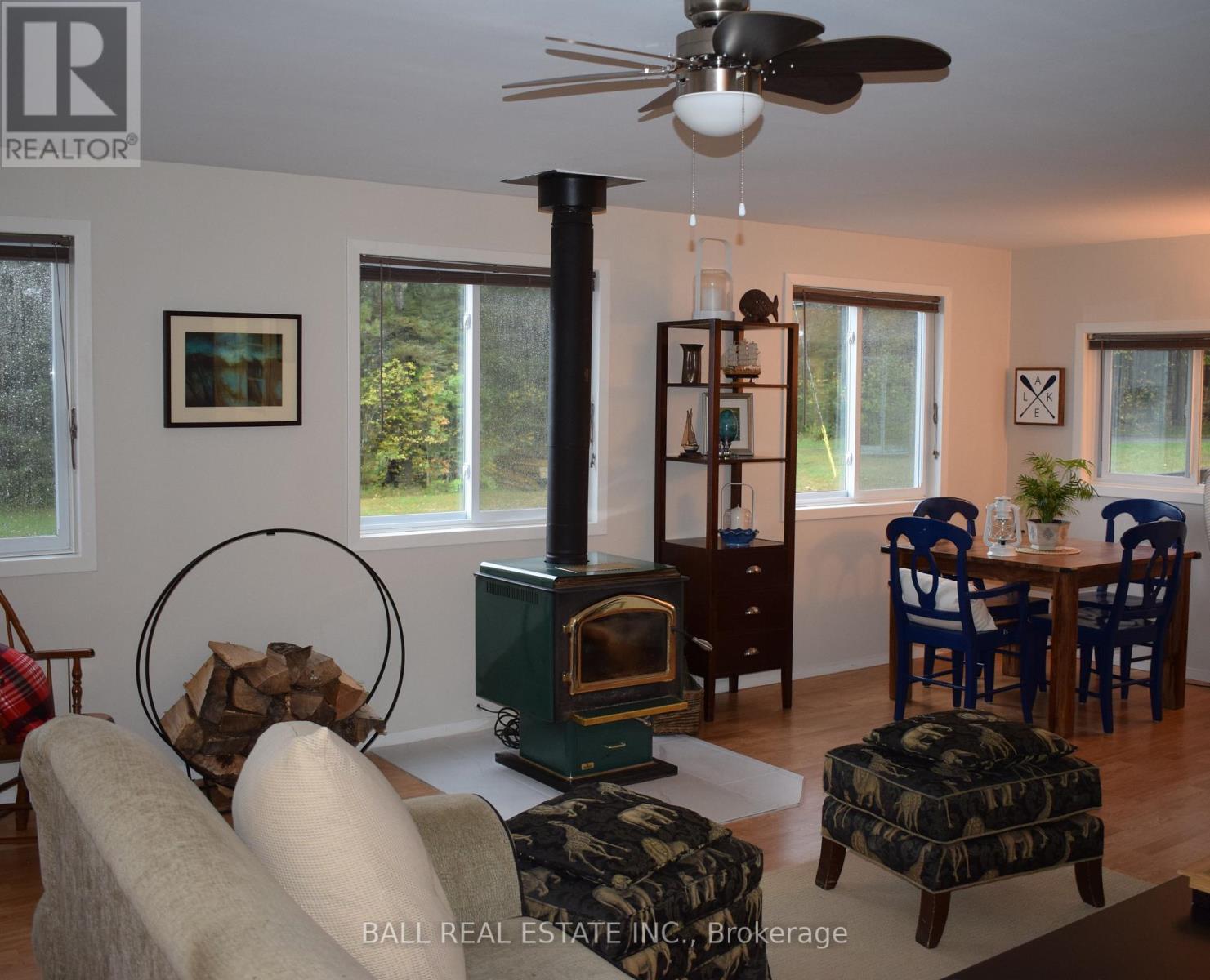 A living room with a wood stove and a fan.