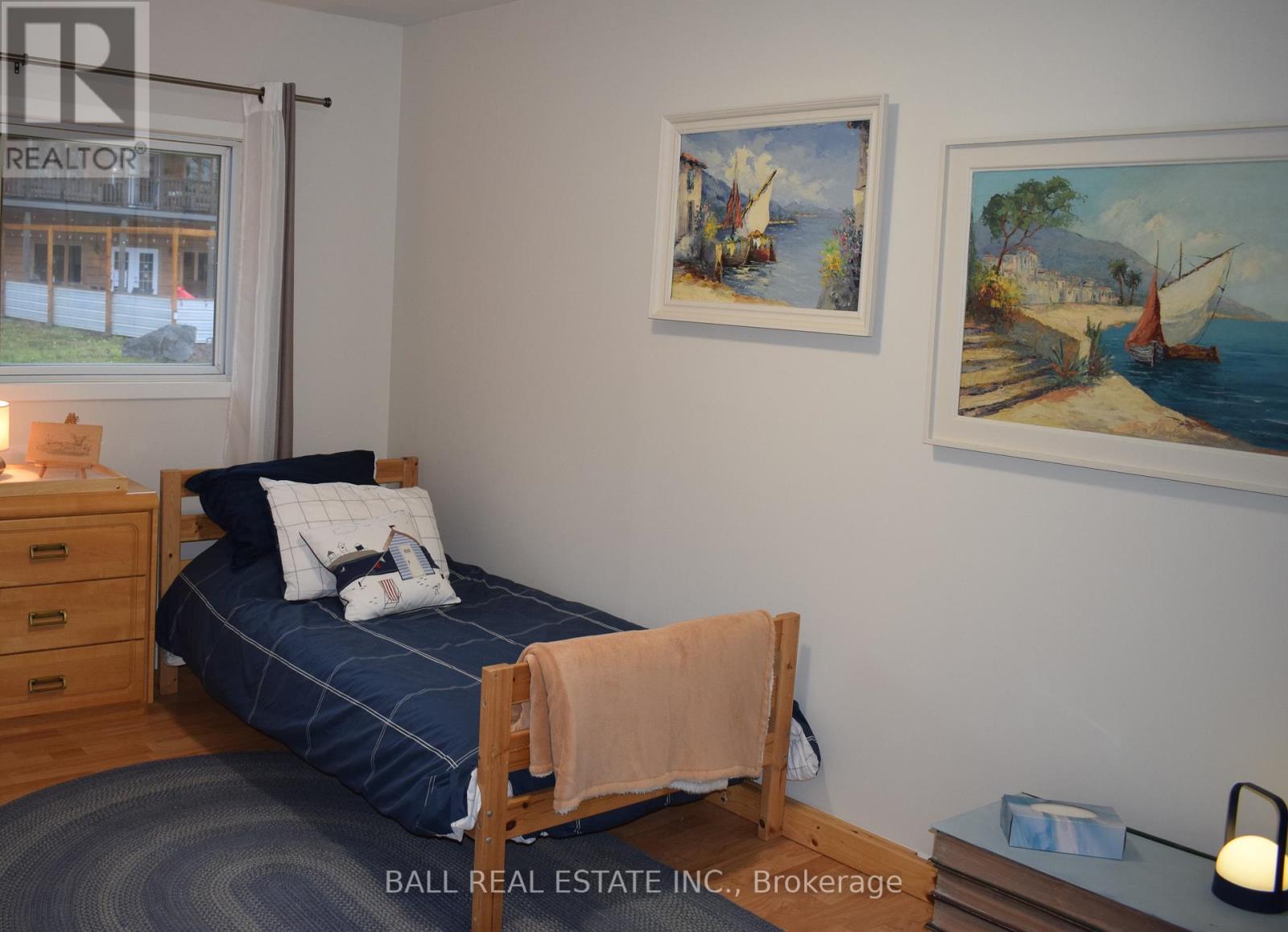 A bedroom with a bed, a nightstand, and two pictures on the wall.