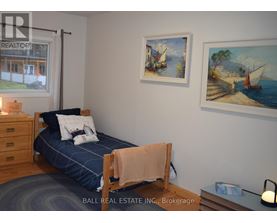 A bedroom with a bed, a nightstand, and two pictures on the wall.