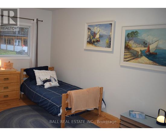 A bedroom with a bed, a nightstand, and two pictures on the wall.