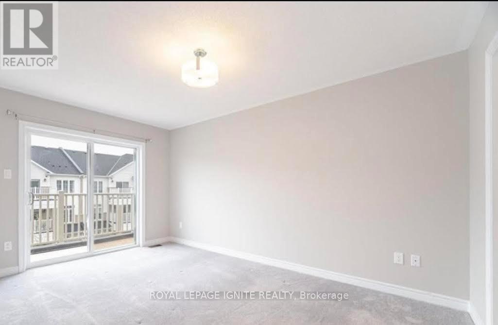A room with a white ceiling and walls, a light fixture on the ceiling, and a doorway leading to another room.