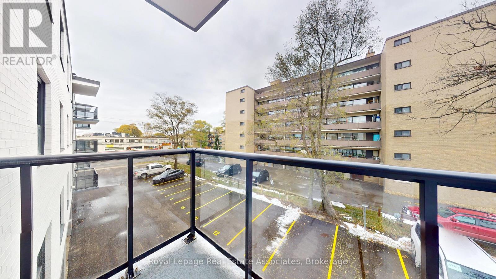 A balcony view of a parking lot and apartment buildings.