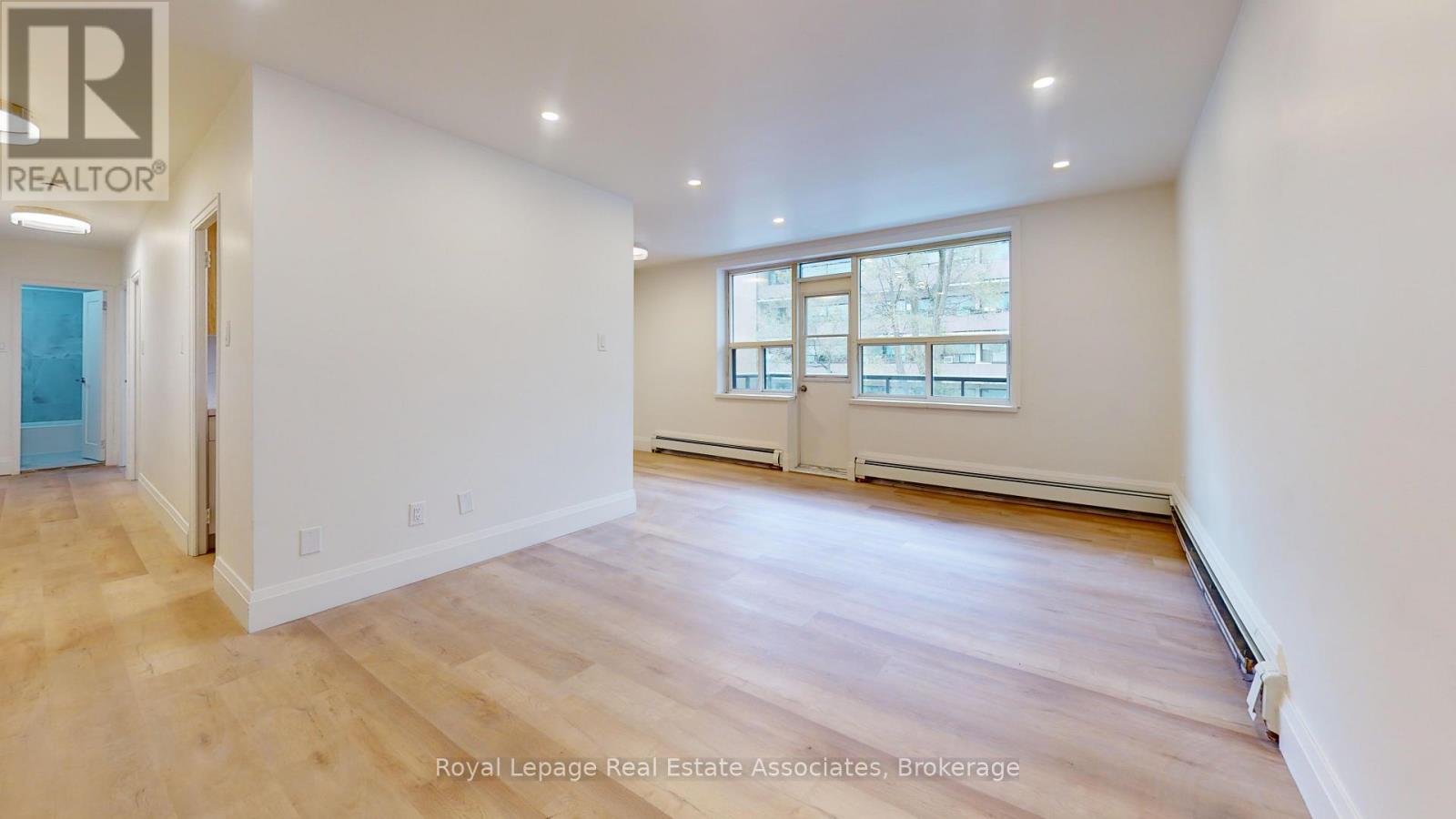 A spacious room with wooden flooring and white walls.