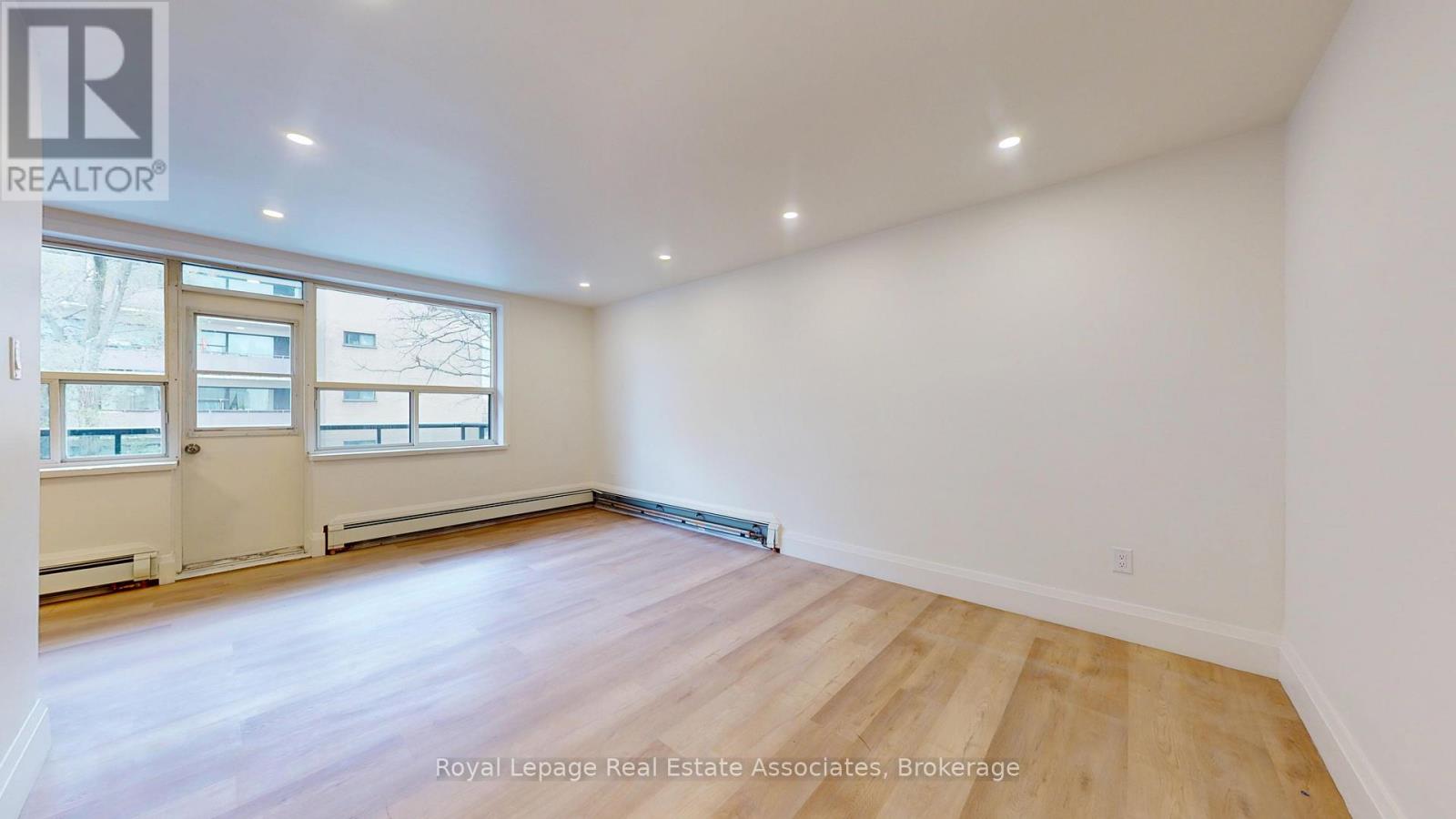 A large, empty room with wooden flooring and white walls.