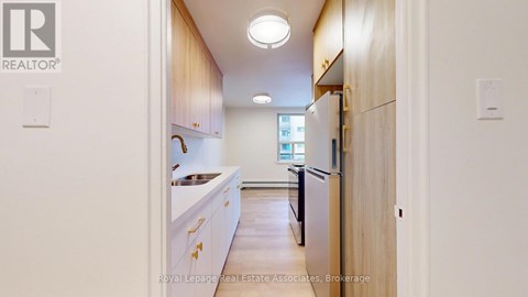 A kitchen with white cabinets and a black refrigerator.