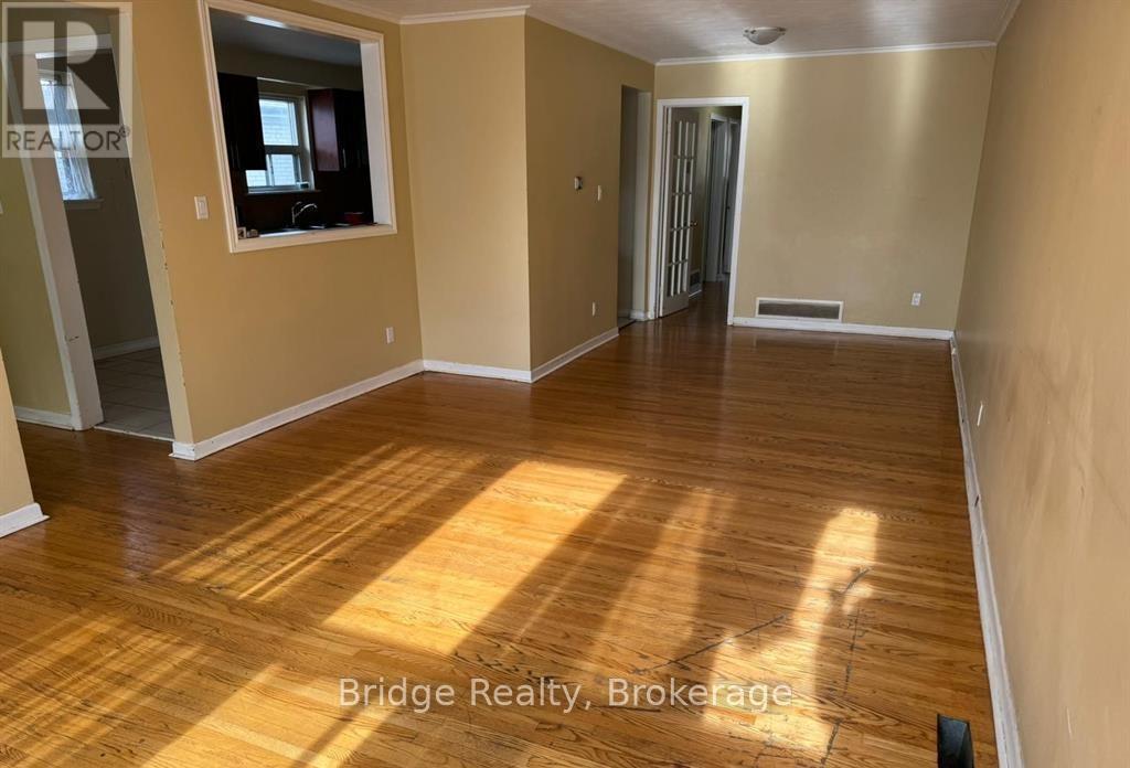A spacious room with wooden flooring and a window.
