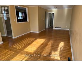 A spacious room with wooden flooring and a window.