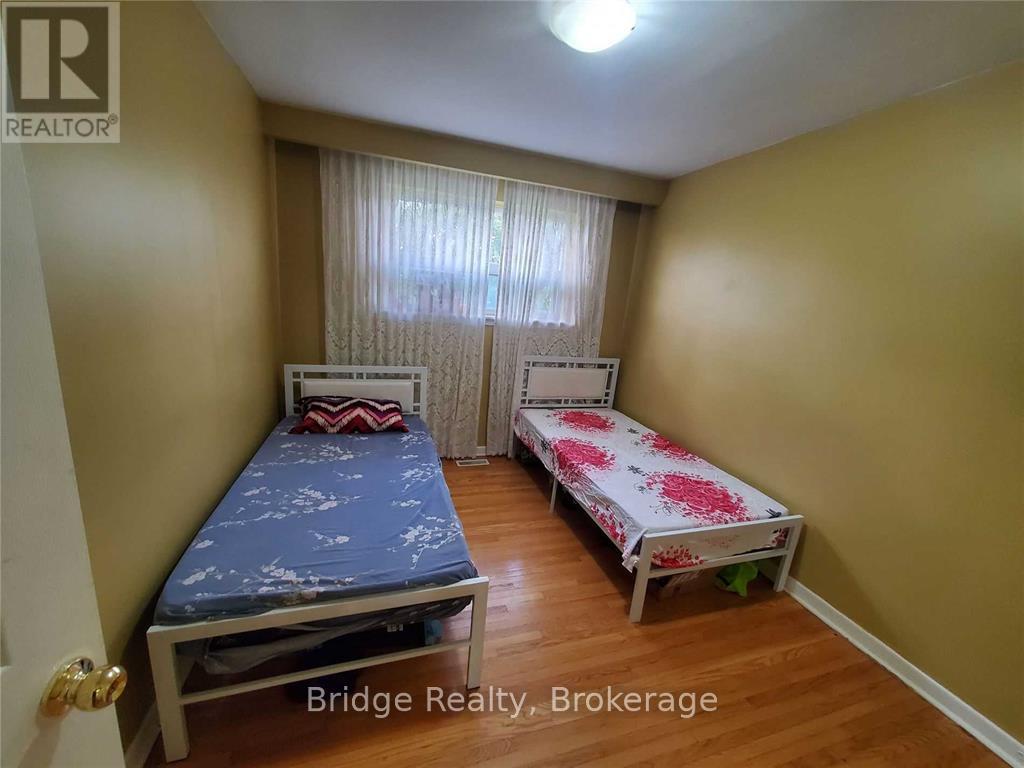 A bedroom with two beds and a window with curtains.
