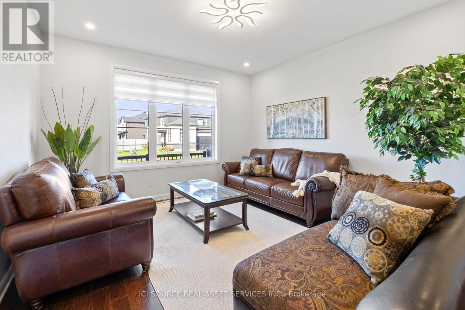 A living room with brown leather furniture and a large window.
