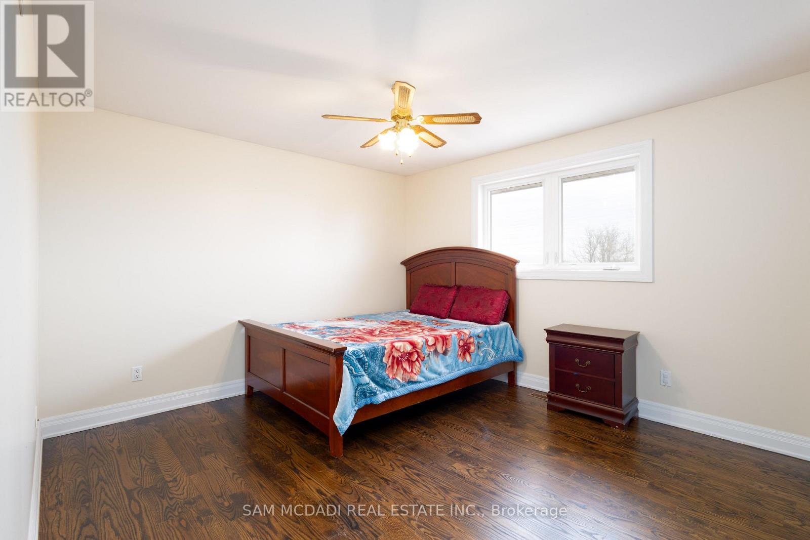 A bedroom with a bed, a ceiling fan, and a small table.