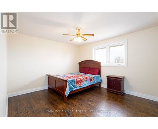 A bedroom with a bed, a ceiling fan, and a small table.