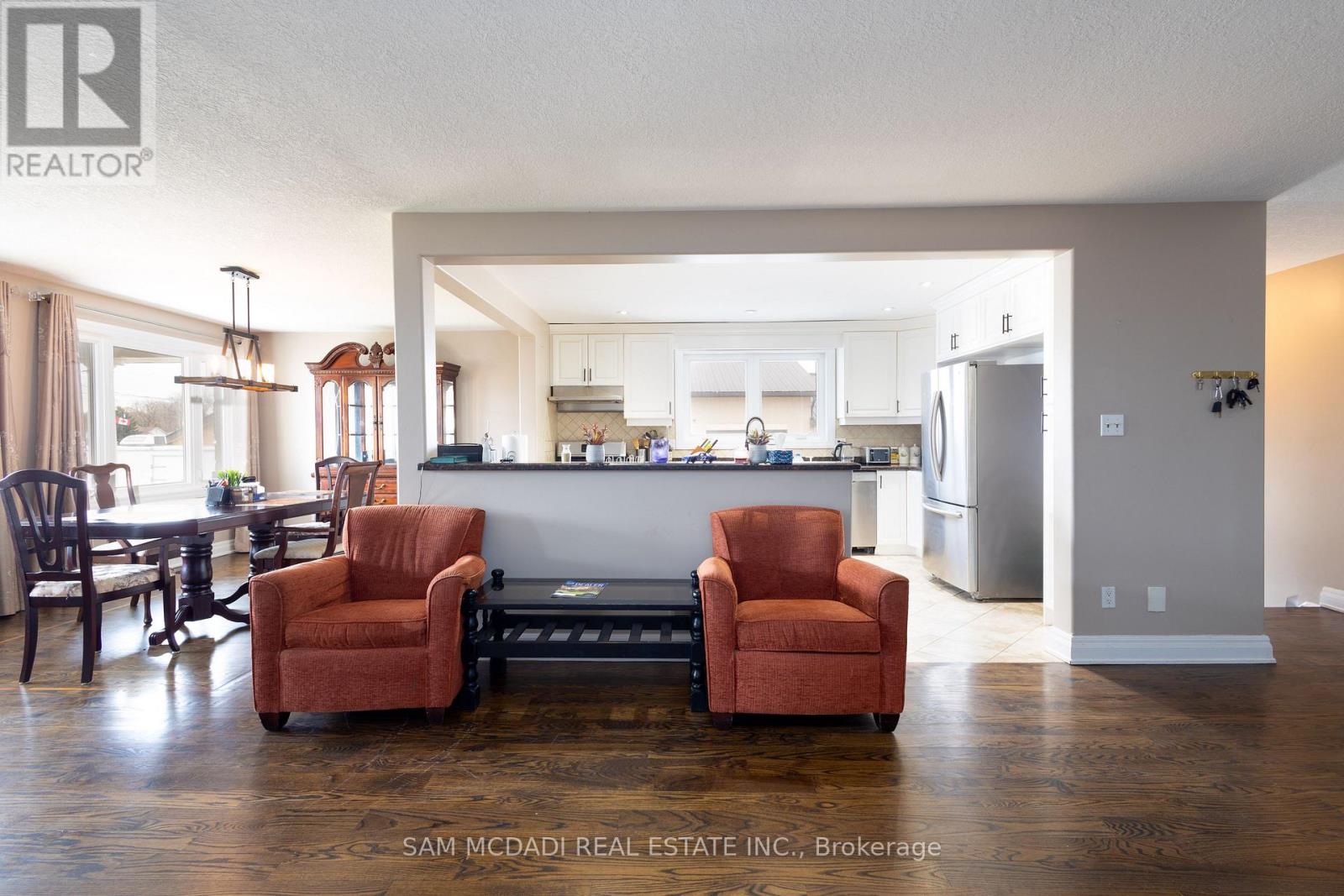 A kitchen with a refrigerator, cabinets, and a dining table with chairs.
