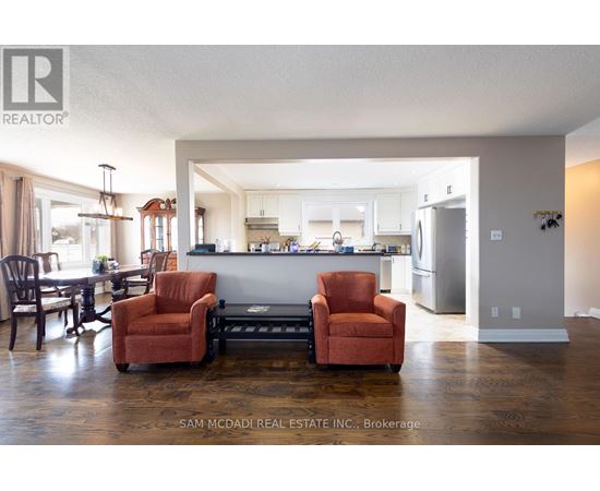 A kitchen with a refrigerator, cabinets, and a dining table with chairs.