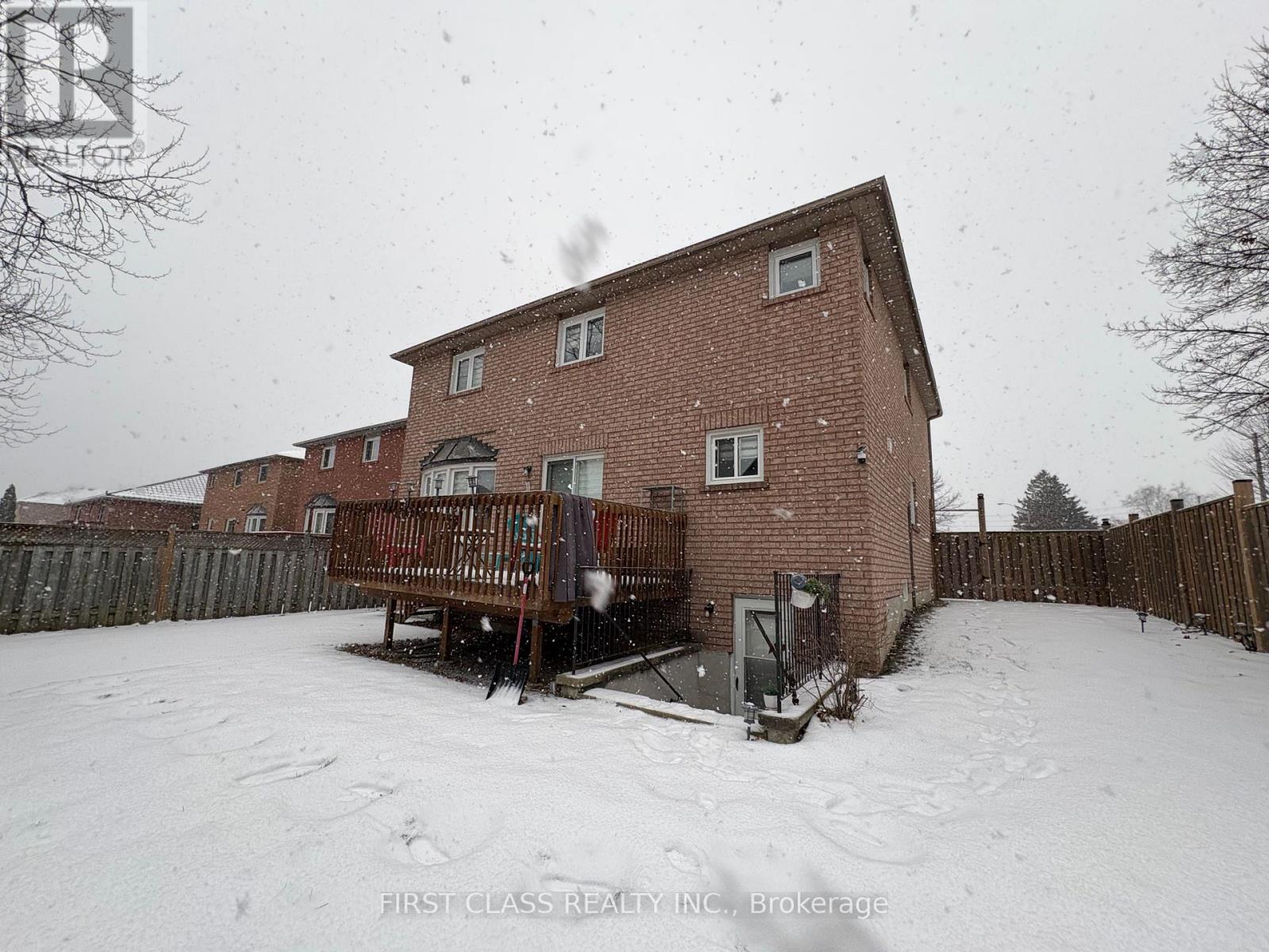 A red brick house with a snow-covered ground and a wooden fence.
