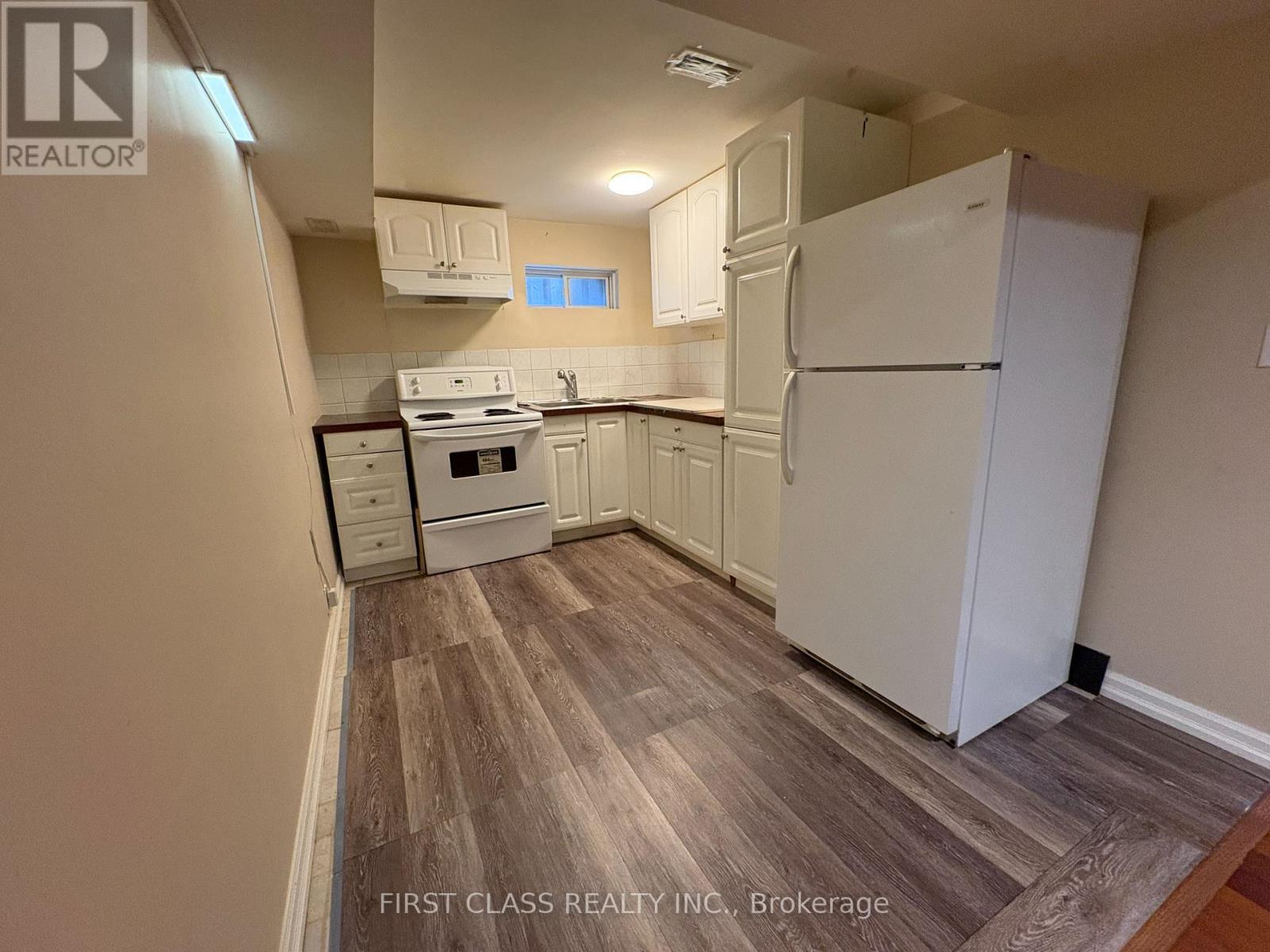 A kitchen with a white refrigerator, oven, and cabinets.