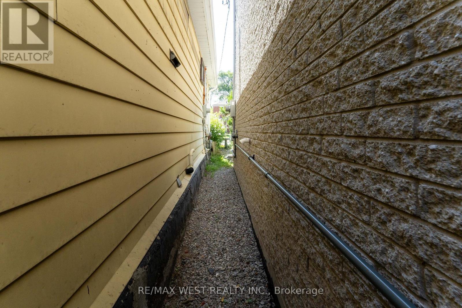A narrow alleyway between two buildings with a brokerage sign on the bottom left.