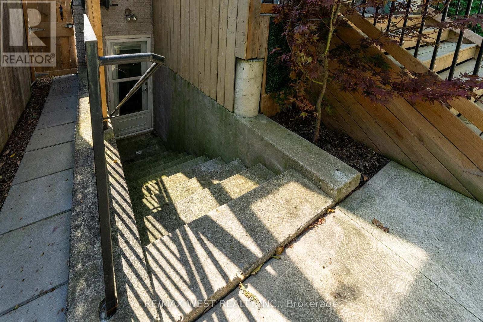 A small, concrete pool area with a ladder and a metal railing.