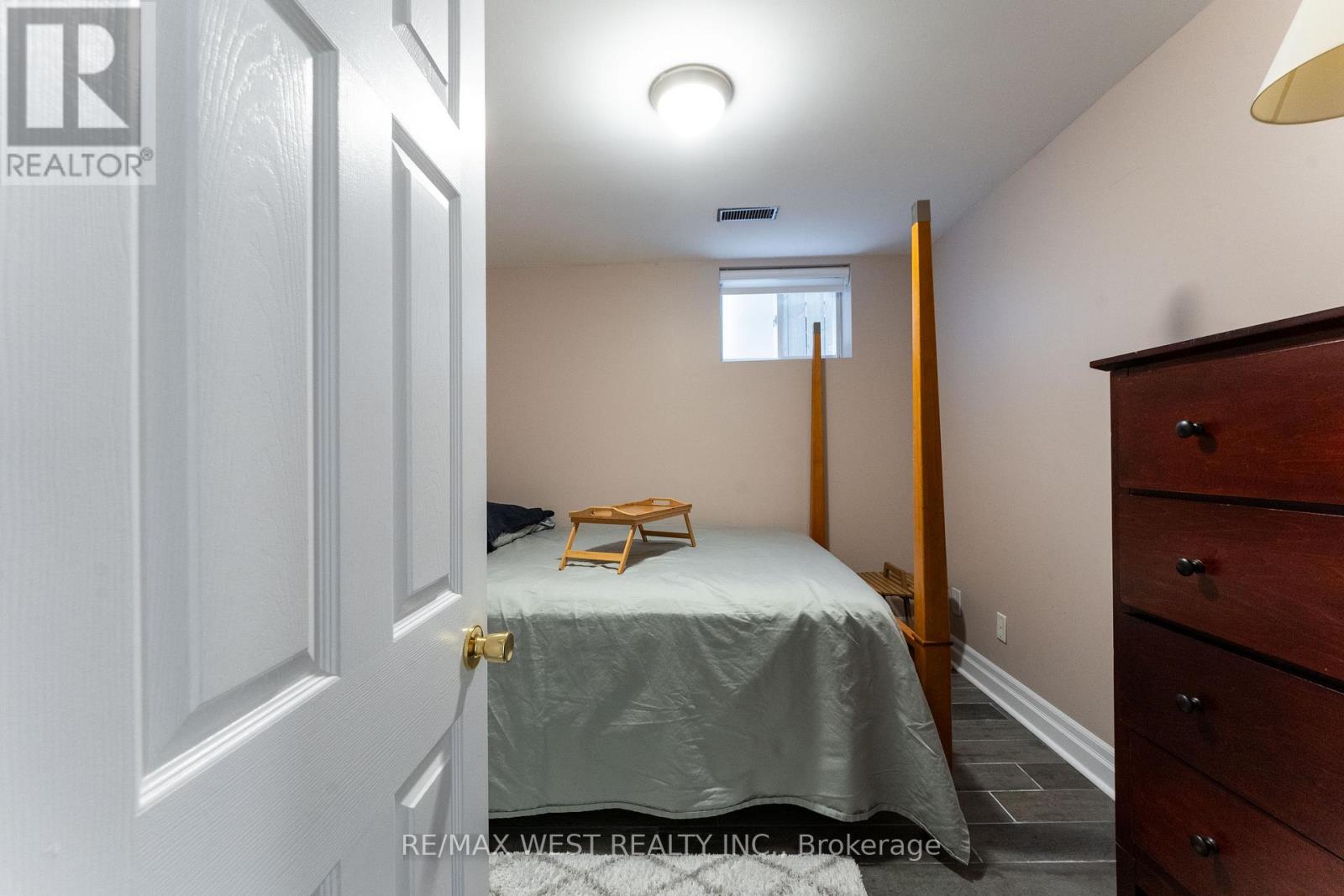 A bedroom with a bed, dresser, and window.
