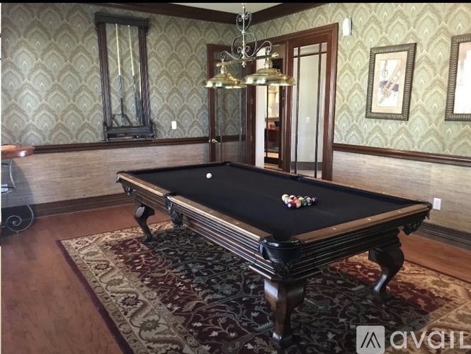 A pool table with a few balls on it in a room with patterned wallpaper.