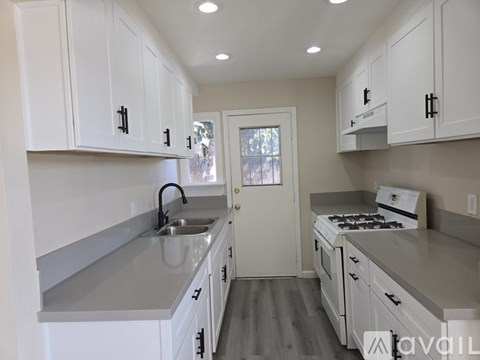 A kitchen with white cabinets and a stove top oven.