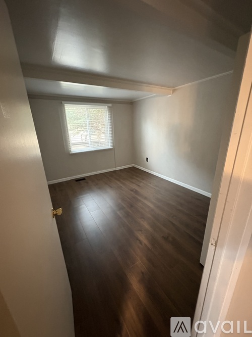 A room with wooden floors and a window with blinds.
