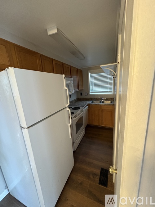 A white refrigerator in a kitchen with wooden cabinets.
