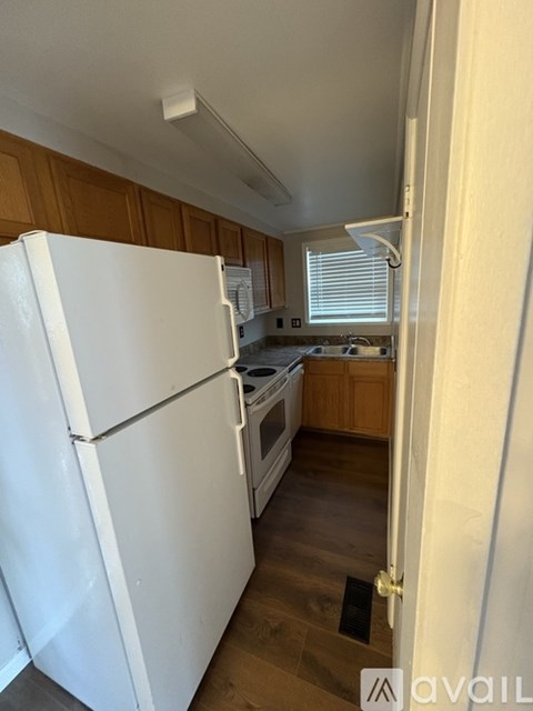 A white refrigerator in a kitchen with wooden cabinets.