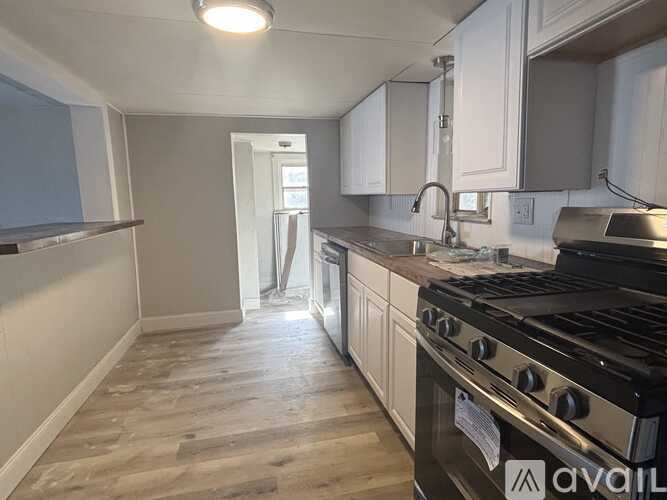 A kitchen with a stove top oven and wooden flooring.