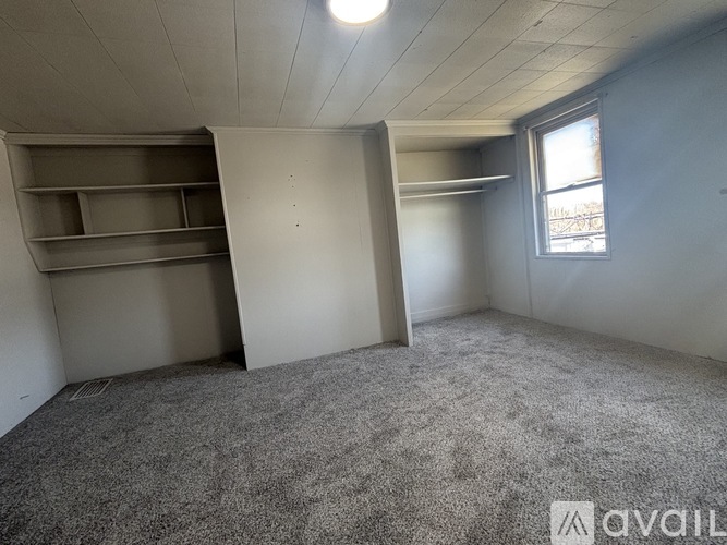 A room with a grey carpet and a window.