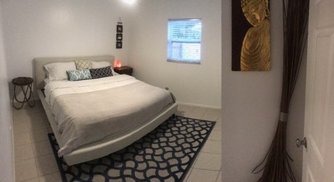 A bedroom with a bed, nightstand, and a framed picture on the wall.