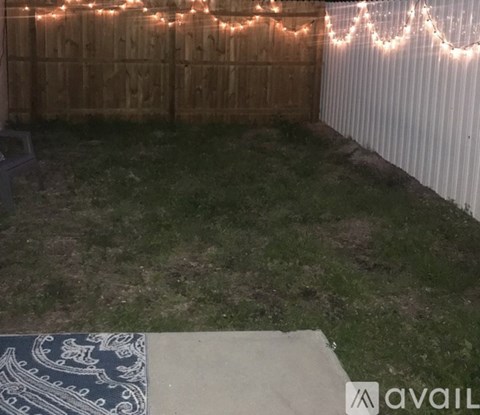 A backyard with a wooden fence and string lights.