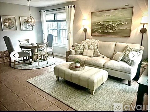 A living room with a white couch and a rug.