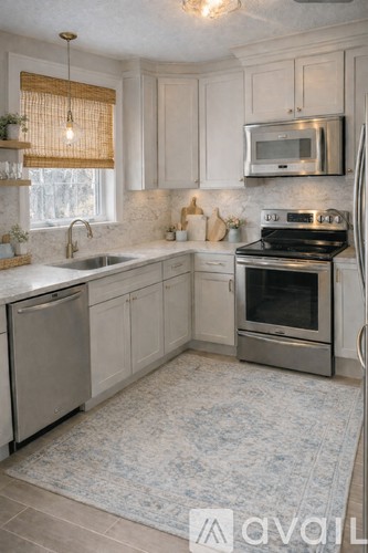 A kitchen with white cabinets and a stainless steel refrigerator.