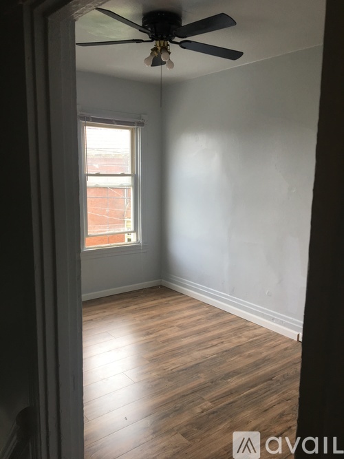 A room with a ceiling fan and wooden flooring.