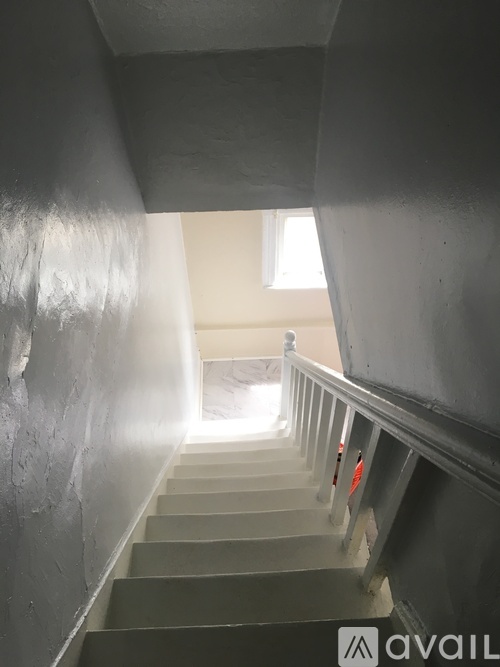 A staircase with a metal railing and steps leading to a light source.