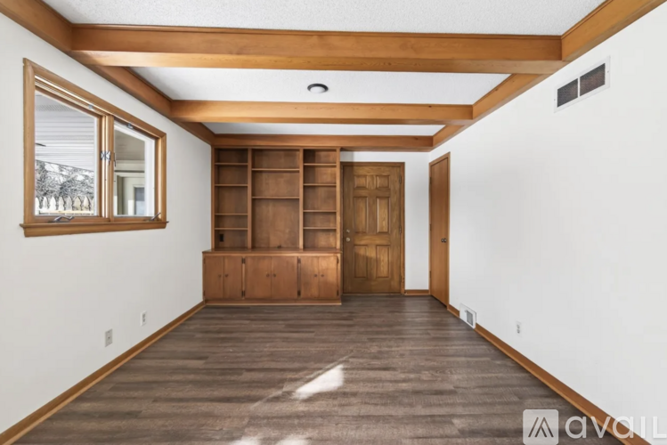 A spacious room with wooden floors and a large wooden bookcase.