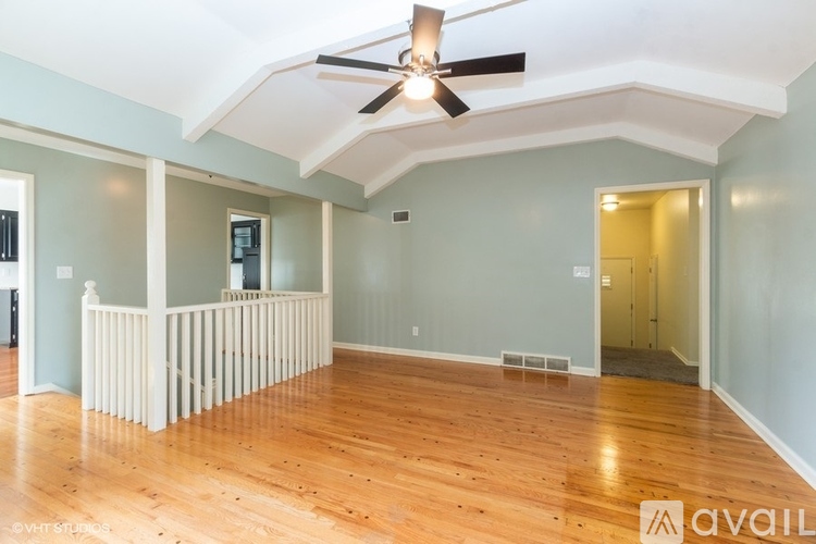 A spacious room with a ceiling fan and hardwood floors.