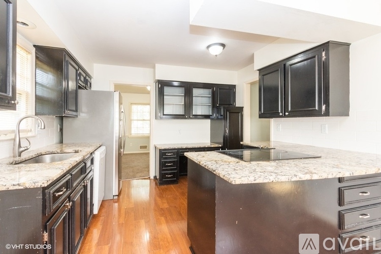 A kitchen with black cabinets and a marble countertop.